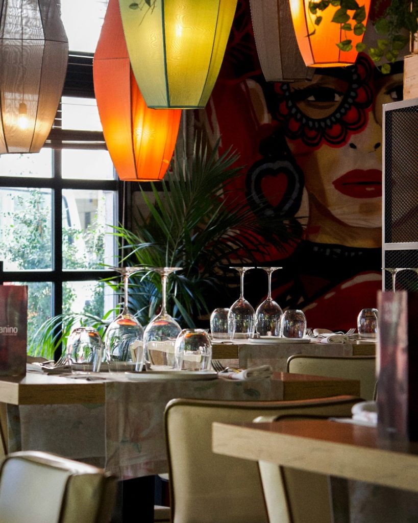Interior del restaurante Tanino con lámparas de colores y mural artístico